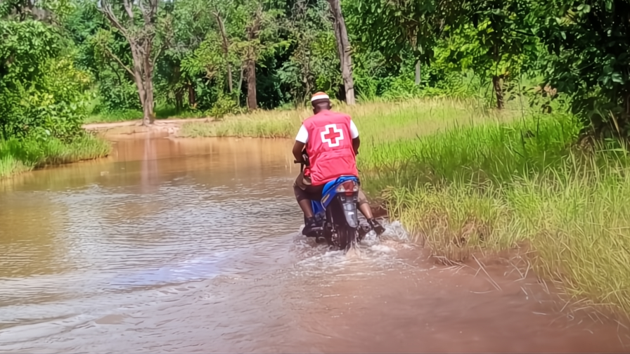 A Mali Red Cross volunteer rides through flood water on his motorbike to reach communities affecting by flooding in late 2024 and make sure children continue to receive their routine immunizations.