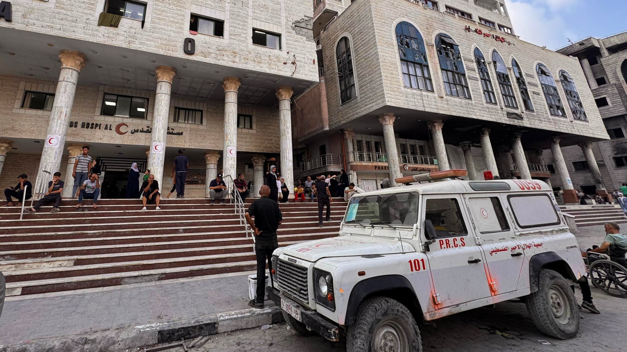 People sit outside Al-Quds hospital in Gaza City, run by the Palestine Red Crescent Society, which has faced repeated strikes during the conflict.
