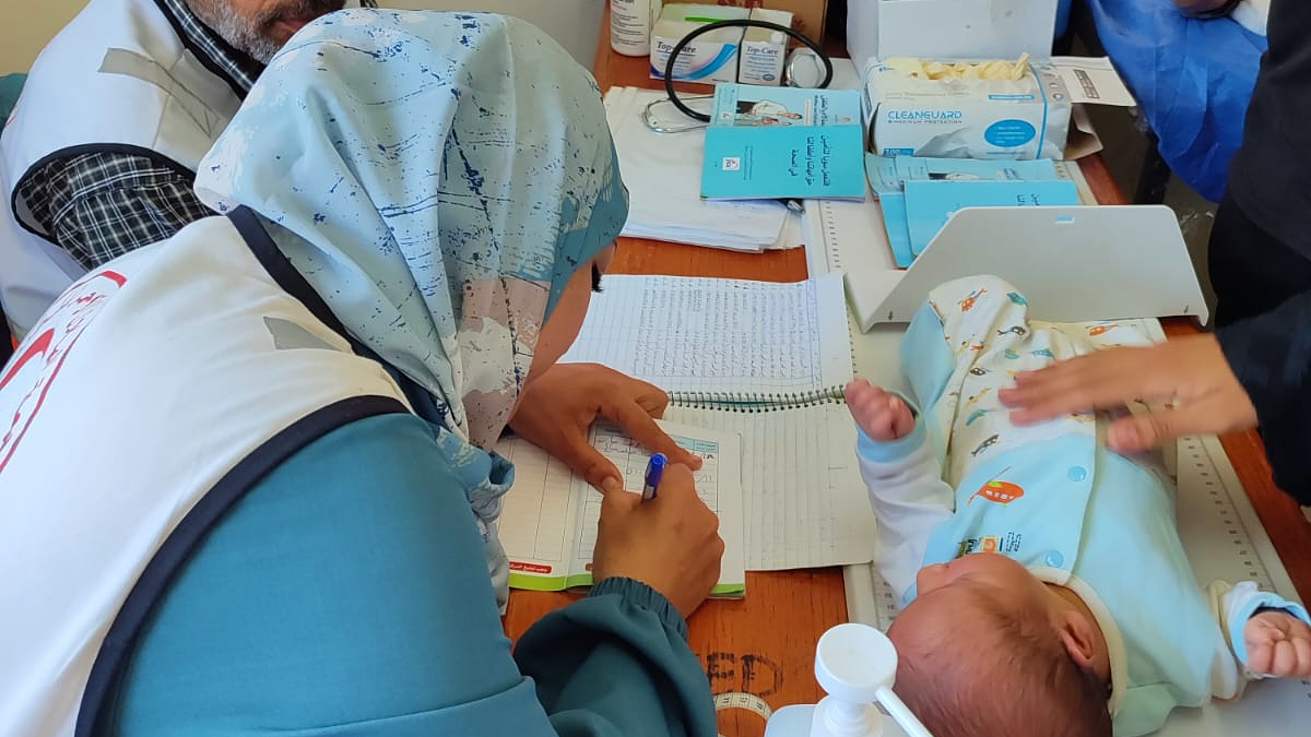 Palestine Red Crescent Society medical staff perform a checkup and administer routine immunizations to a baby at a medical point in June 2025.