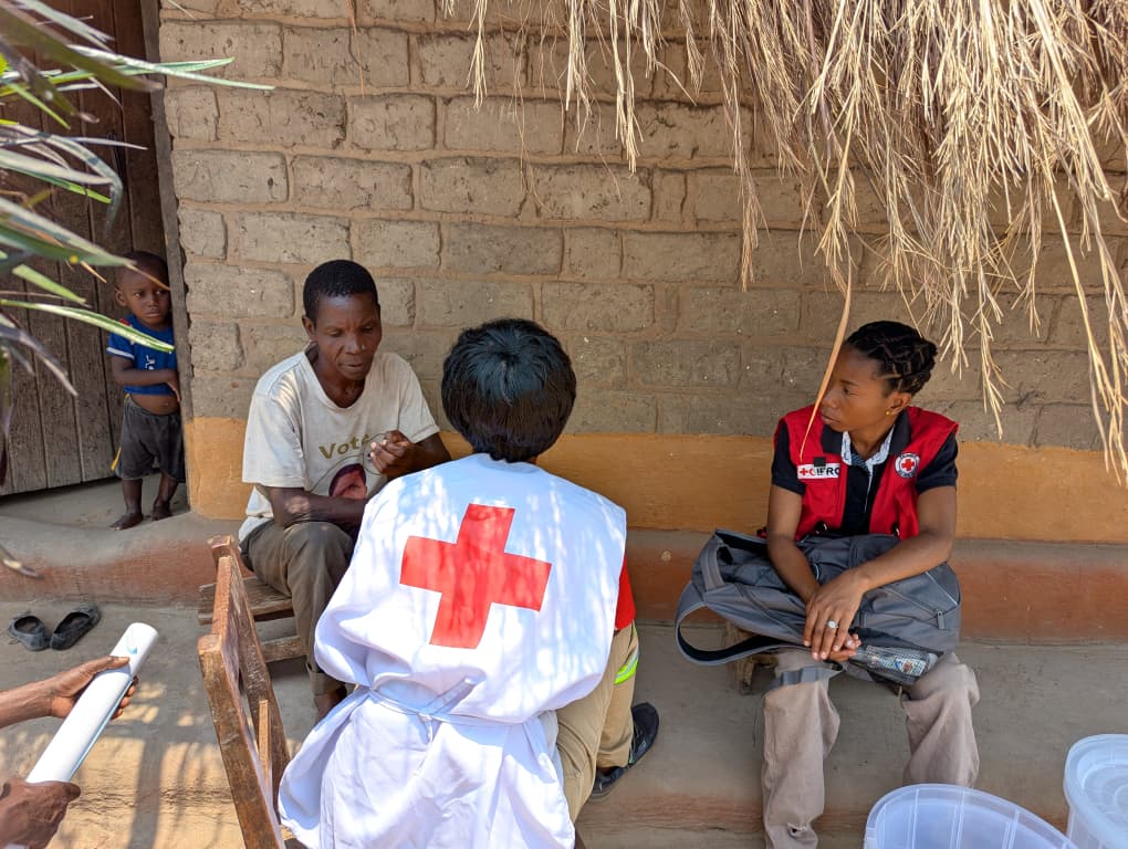 A Red Cross volunteer engages a family in Mpulungu during a household visit, sharing information on cholera prevention and early symptom recognition.