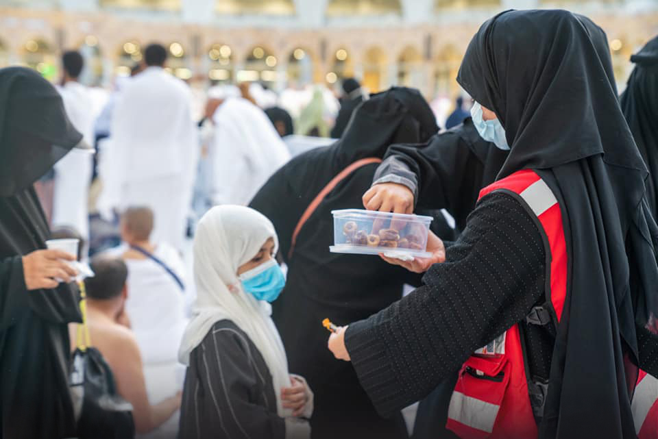 A Saudi Red Crescent volunteer offers a snack to a child during Hajj. Across Saudi Arabia, volunteers provide comfort and care in many settings, from assisting pilgrims during Hajj to bringing hope to children with cancer. 