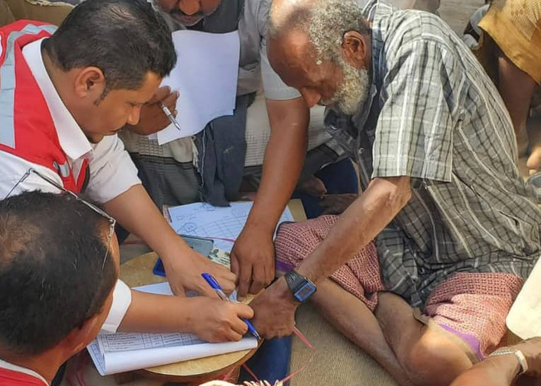Yemen Red Crescent volunteers supporting community members during a field activity involving form completion. 