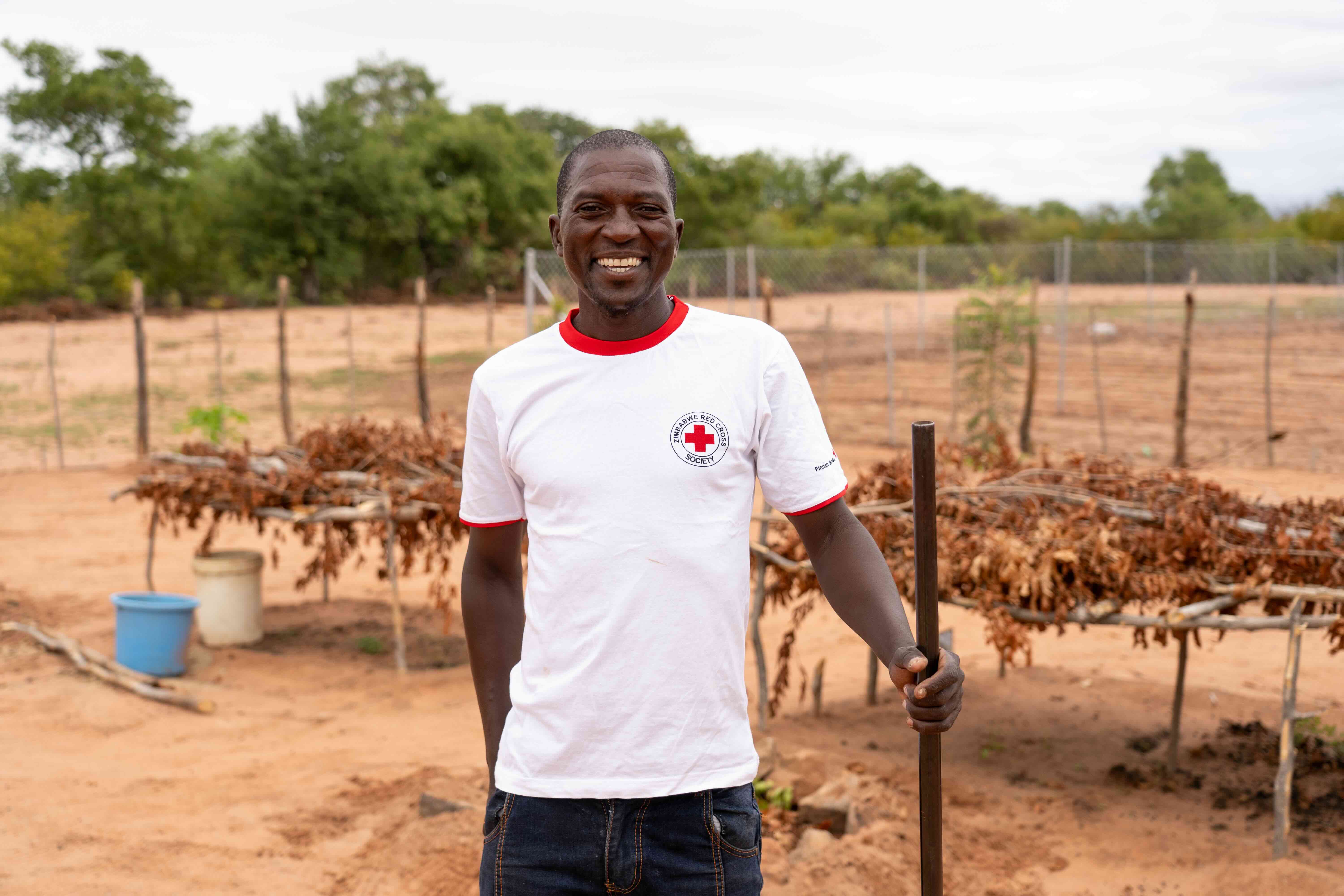 A volunteer with the Zimbabwe Red Cross stands in front the community garden in Binga, Zimbabwe.