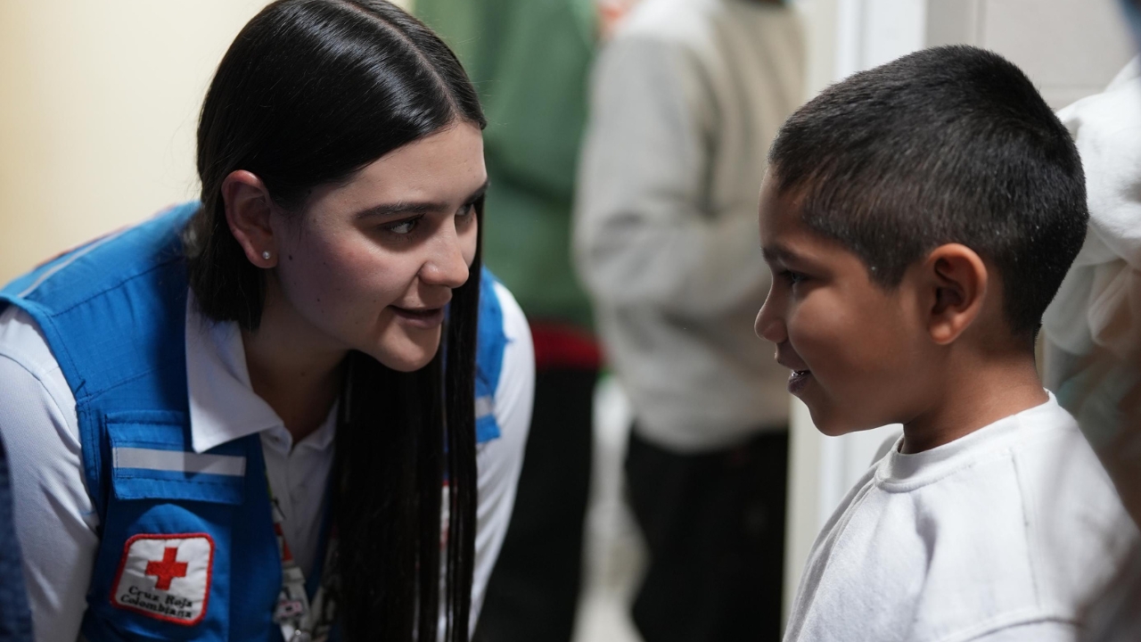 Elizabeth Becerra, leader of the Colombian Red Cross migration team, talks with a child who arrived on a return flight to El Dorado Airport. 