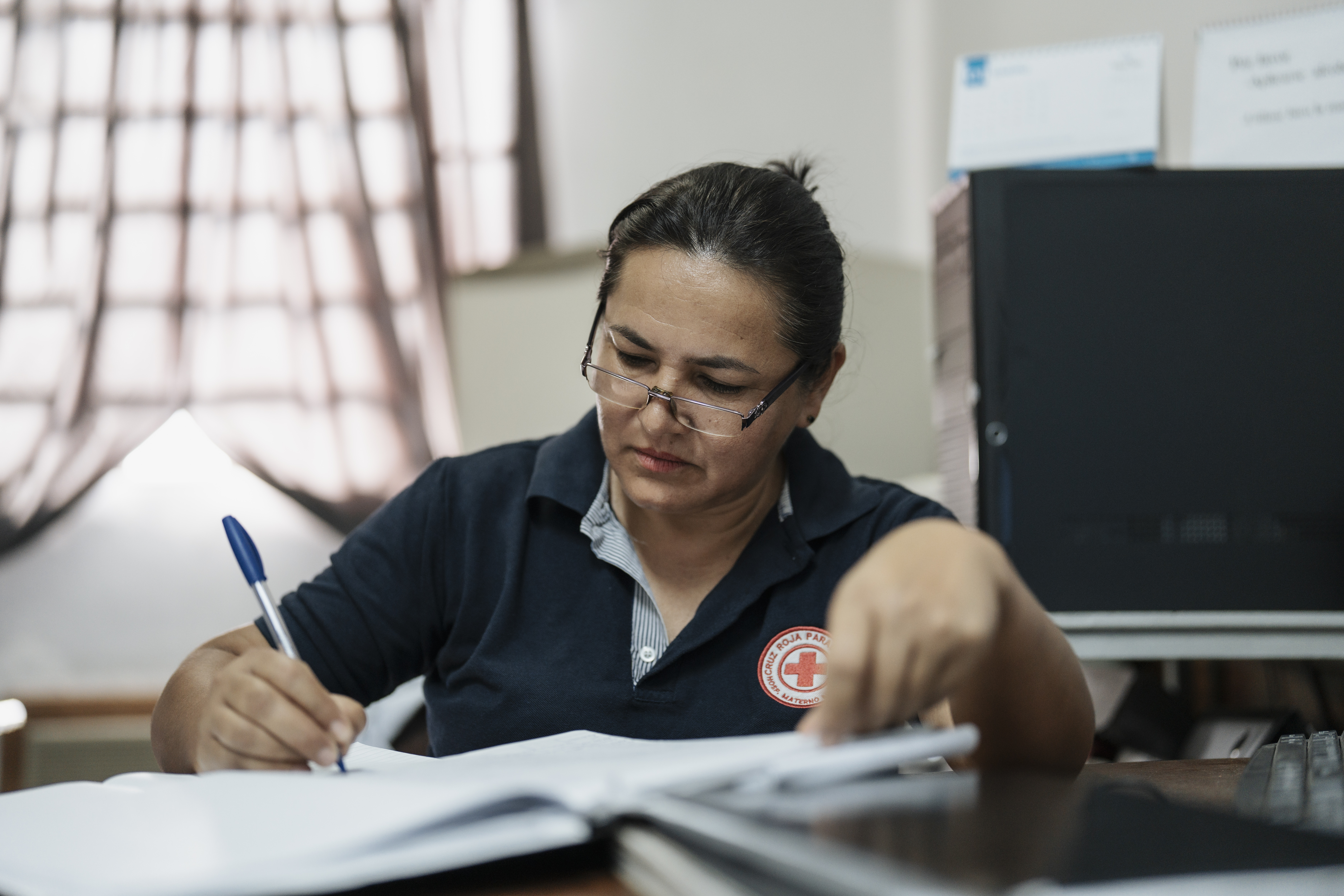 A woman from the Paraguayan Red Cross filling out documents in an office at Reina Sofía Hospital.