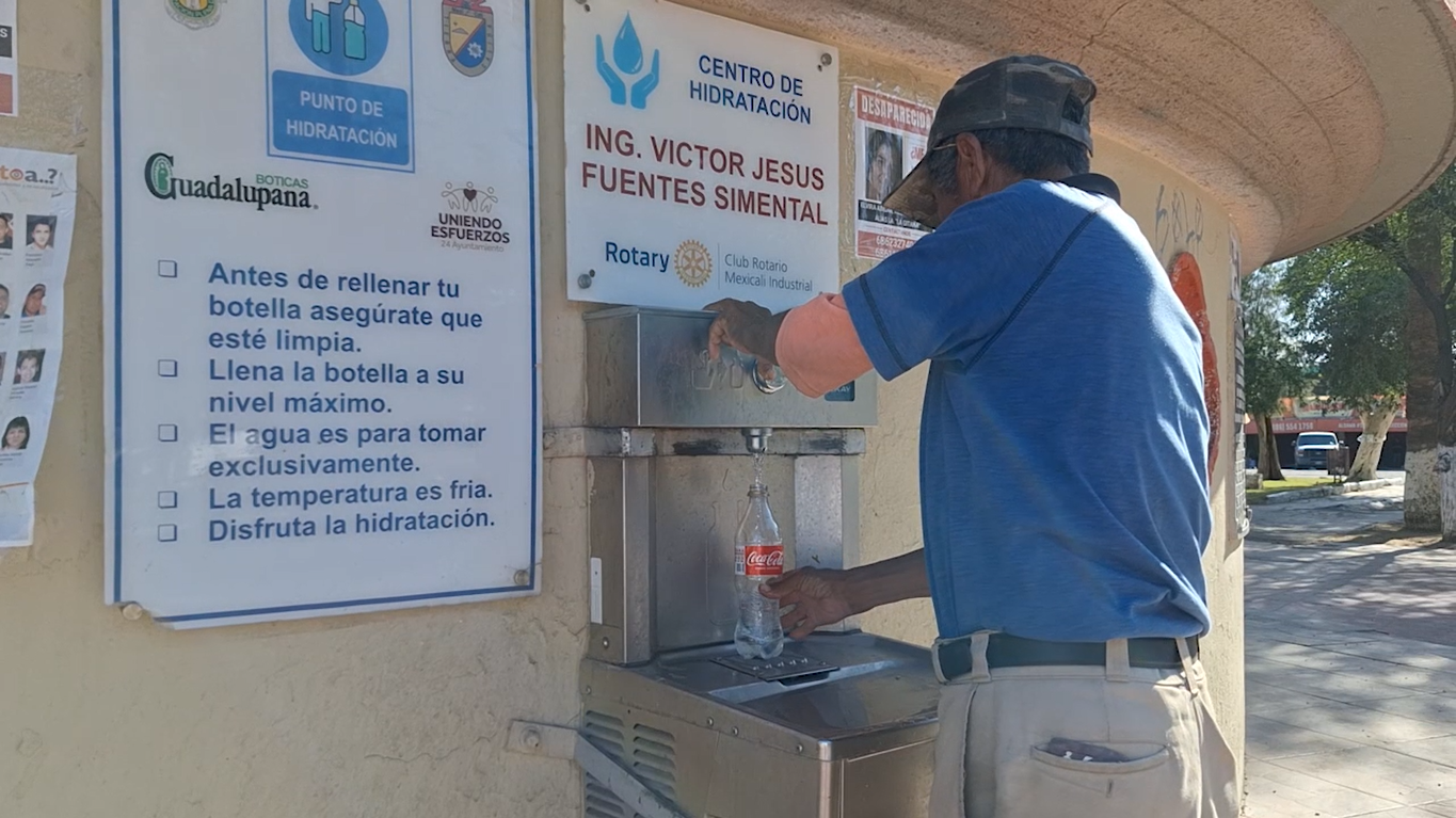 A man in Baja California, Mexico, fills a plastic bottle from a “hydratation point,” during a hot, dry day on the Plaza del Mariachi, in Mexicali.