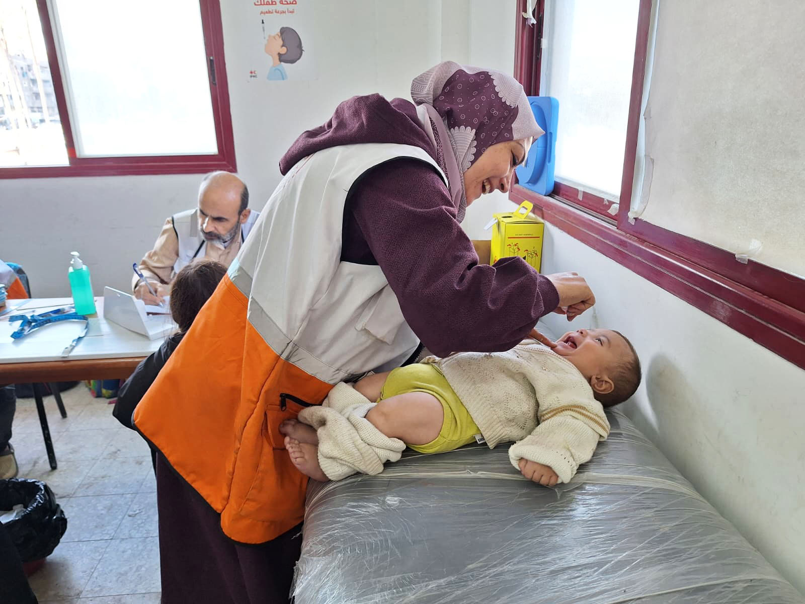 تقوم إحدى العاملات الصحيات في جمعية الهلال الأحمر الفلسطيني بإعطاء لقاح لطفل خلال حملة استكمال التطعيمات في غزة.  