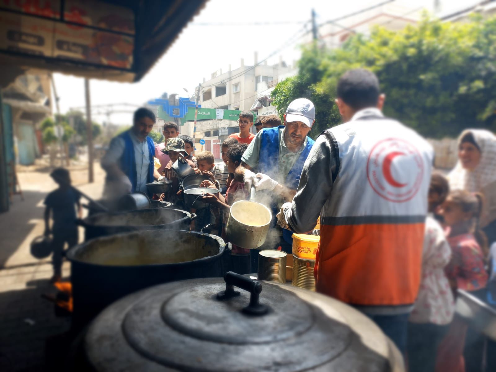 متطوعو جمعية الهلال الأحمر الفلسطيني يُعدّون ويوزّعون وجبات ساخنة على الأسر المتأثرة بالأزمة في غزة. ومن خلال المطابخ الميدانية وعمليات التوزيع، تواصل الجمعية دعم الأسر التي تعاني من انعدام حاد في الأمن الغذائي والنزوح.