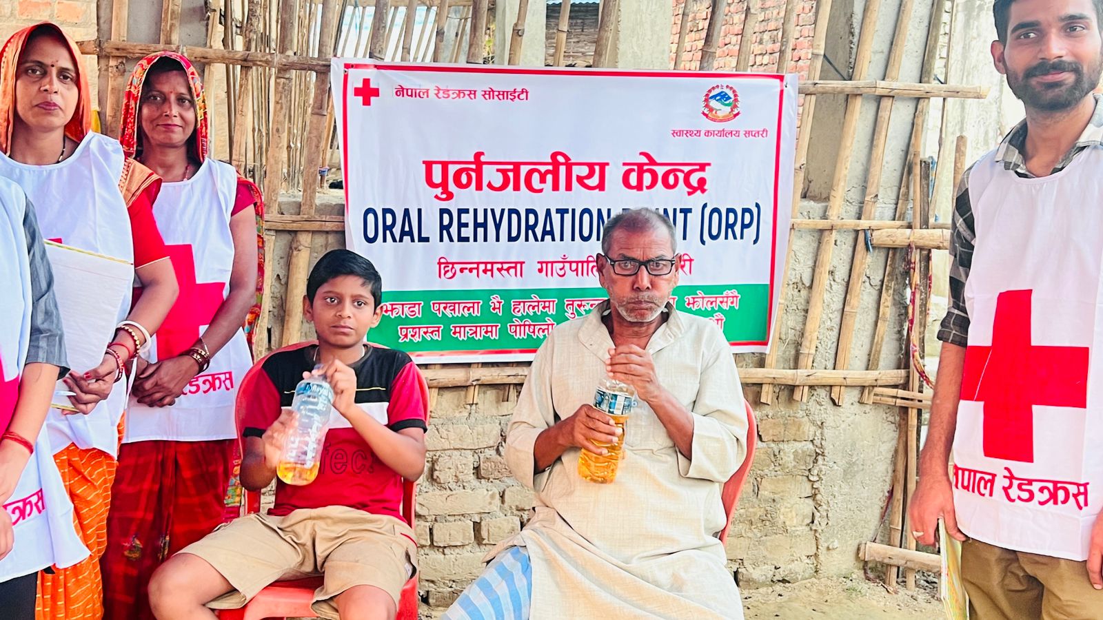 People drink rehydration fluids at an Oral Rehydration Point run by the Nepal Red Cross at a special Cholera clinic set up outside a local hospital in Chhinnamasta.