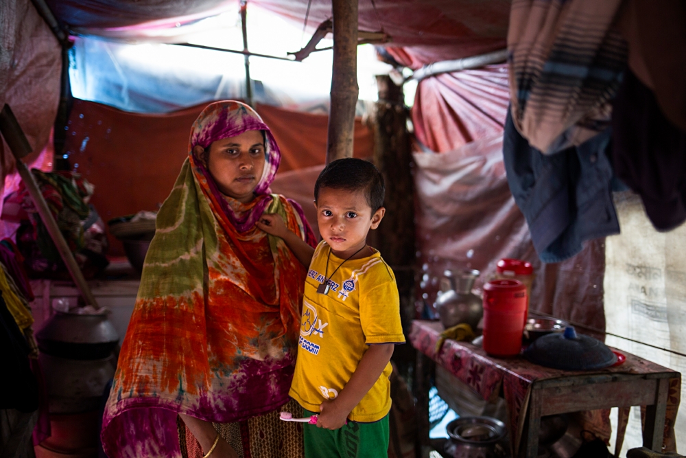Bangladesh, Sirajganj, Aug 2020.A mother and her son standing inside the makeshift shelter they have been living in for the past two months. They received tarpaulins from Bangladesh Red Crescent and I