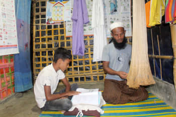 RohomotUllah making fishing net at his shelter while their elder son Anowar Sadek is studying.