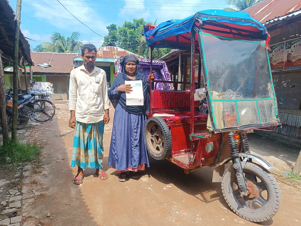 A husband and wife post in front of the auto-rickshaw they recently bought with a small cash grant provided under the flood-recovery operation. Photo: Bangladesh Red Crescent