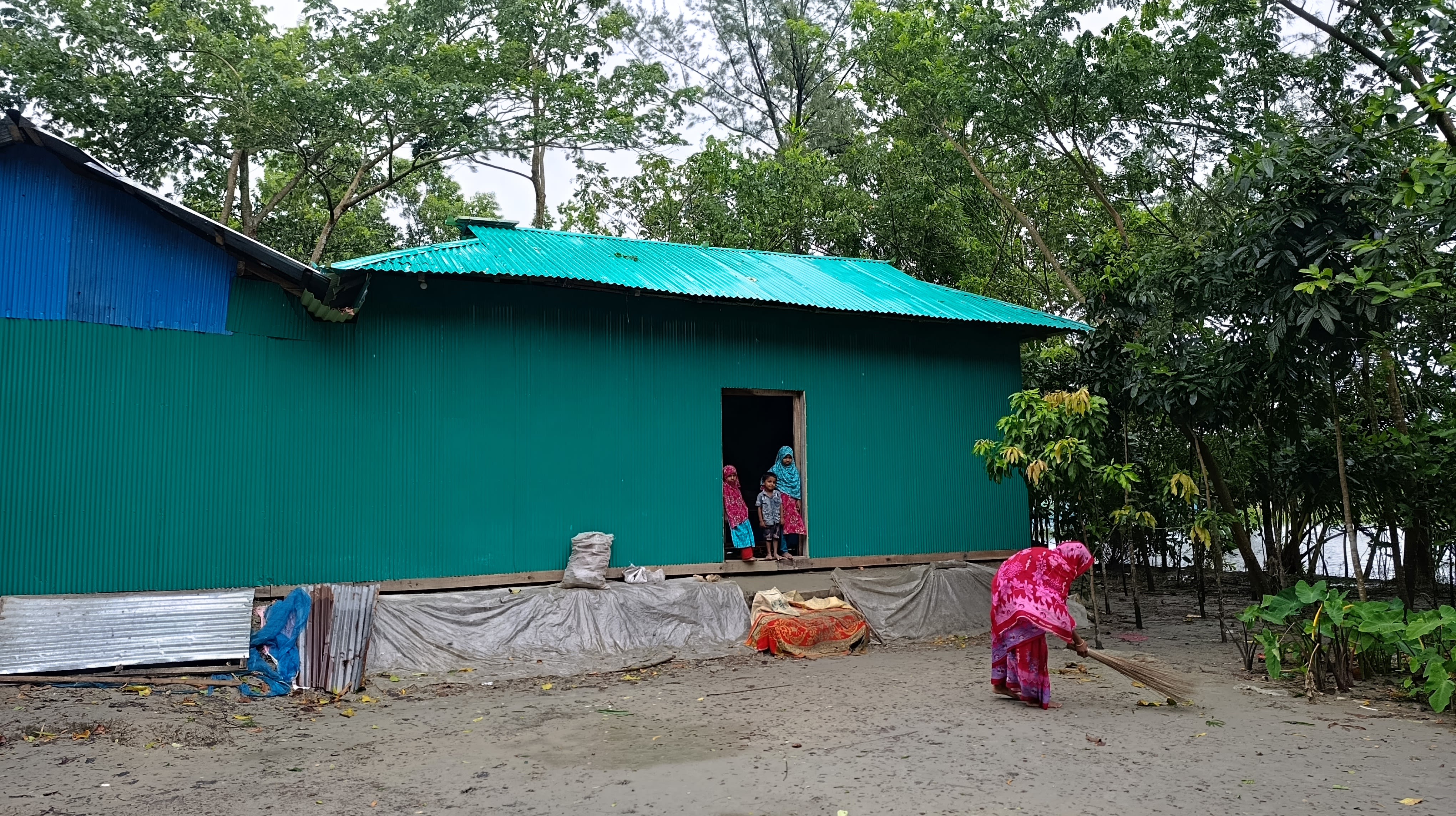 Noyon Akter sweeps up the yard in front of the new shelter provided by the Bangladesh Red Crescent Society, with support from the IFRC. Photo: Bangladesh Red Crescent Society.