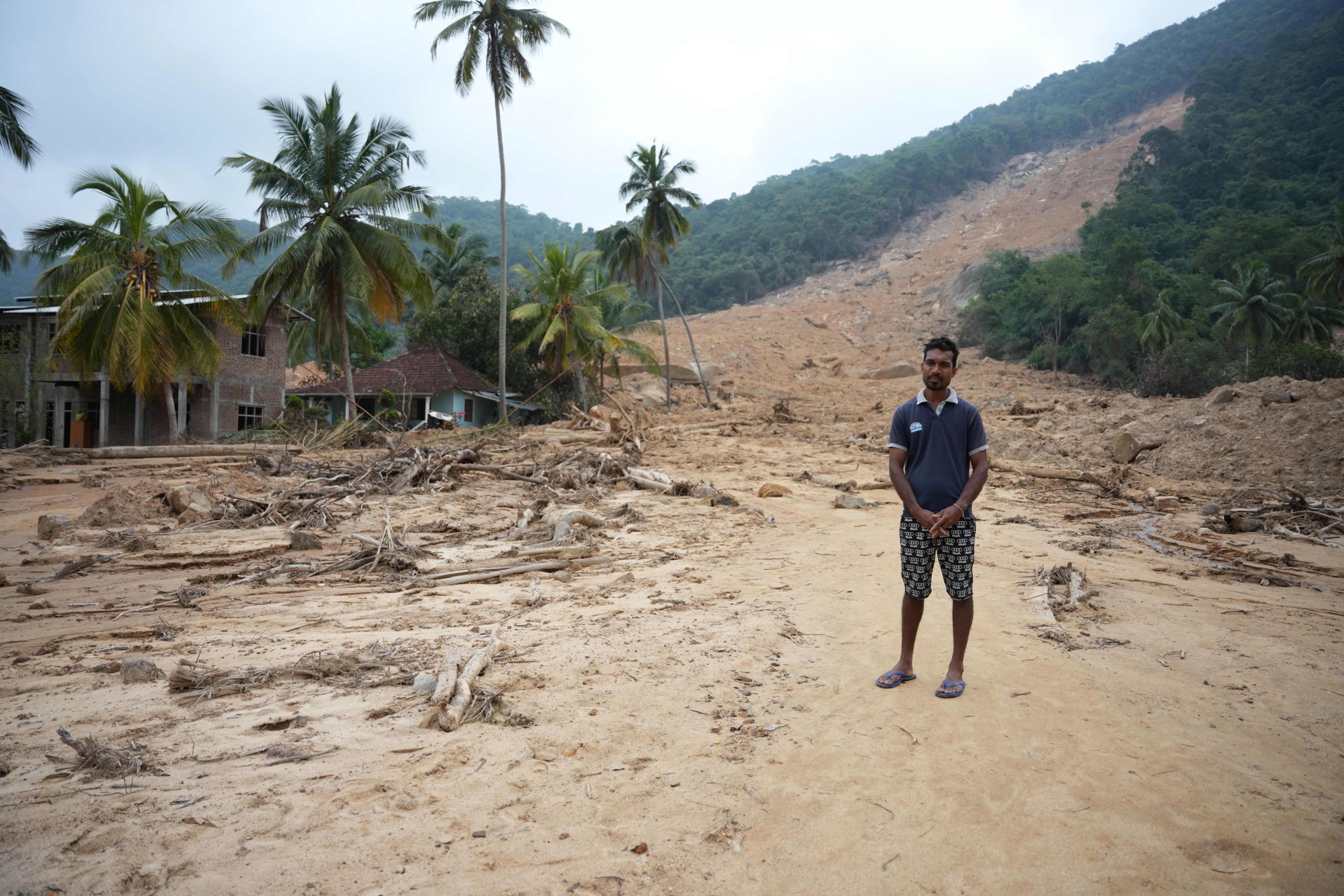 R M A Ratnayke&nbsp;stands in the debris field left by a mudslide that destroyed his home and many others in his village.