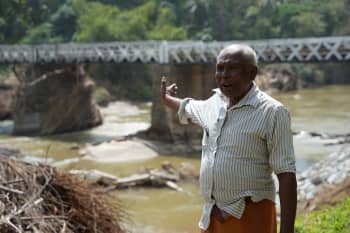 A A Sompala stands near the bridge where his lottery ticket stand was washed away by the floods.