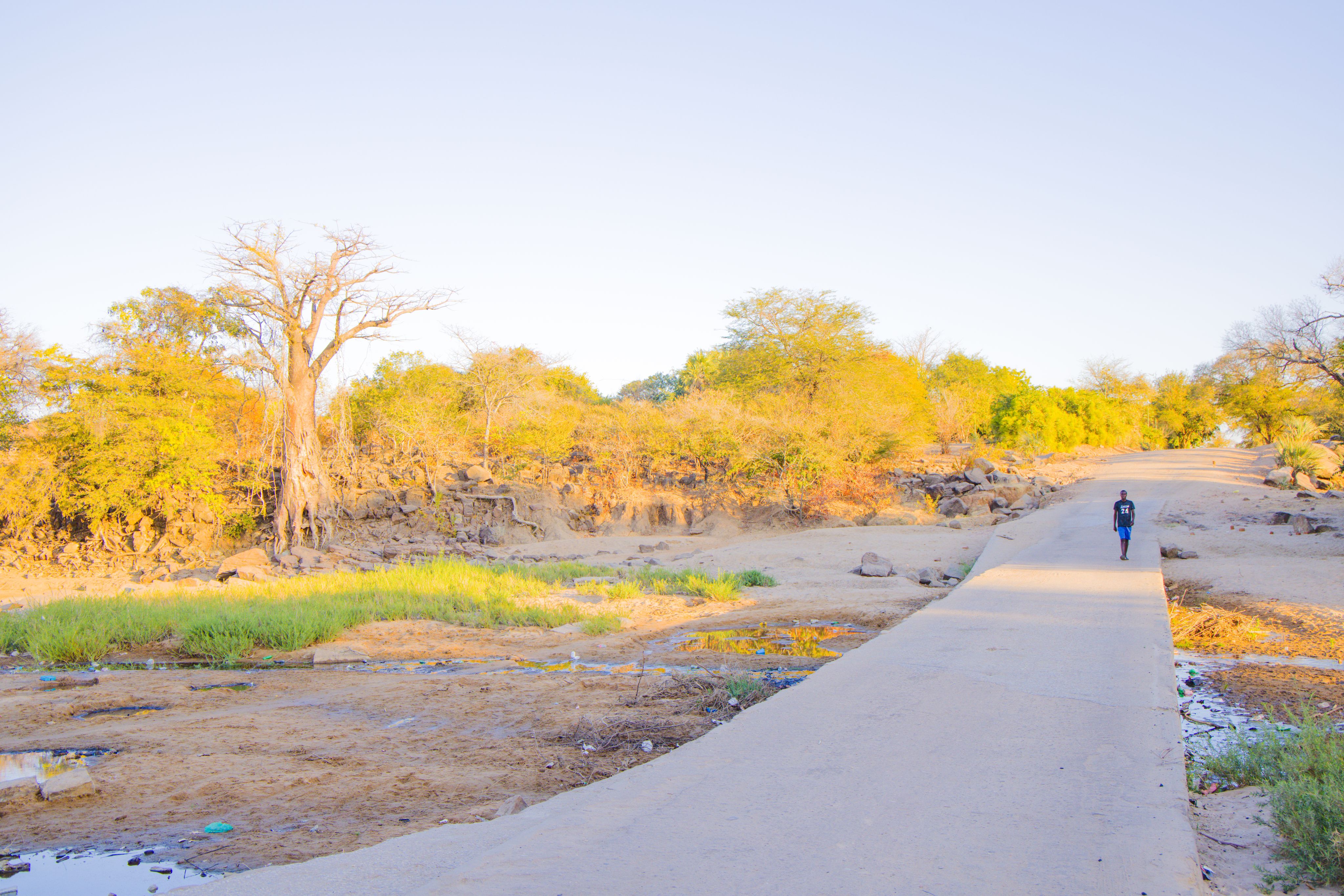 A man walks across a concrete bridge In Sinazongwe, where drought has turned riverbeds into dust trails. 