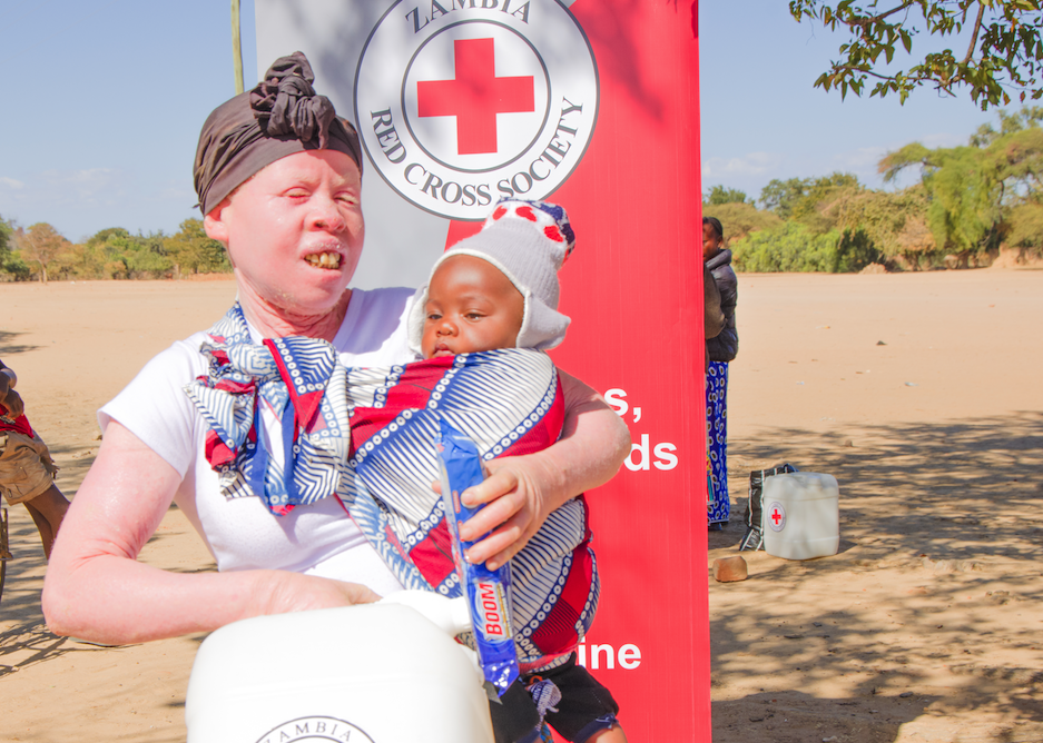 Muleya Sikuteka holds her baby and a 20-litre water container received during a Zambia Red Cross hygiene kit distribution in Sinazongwe.