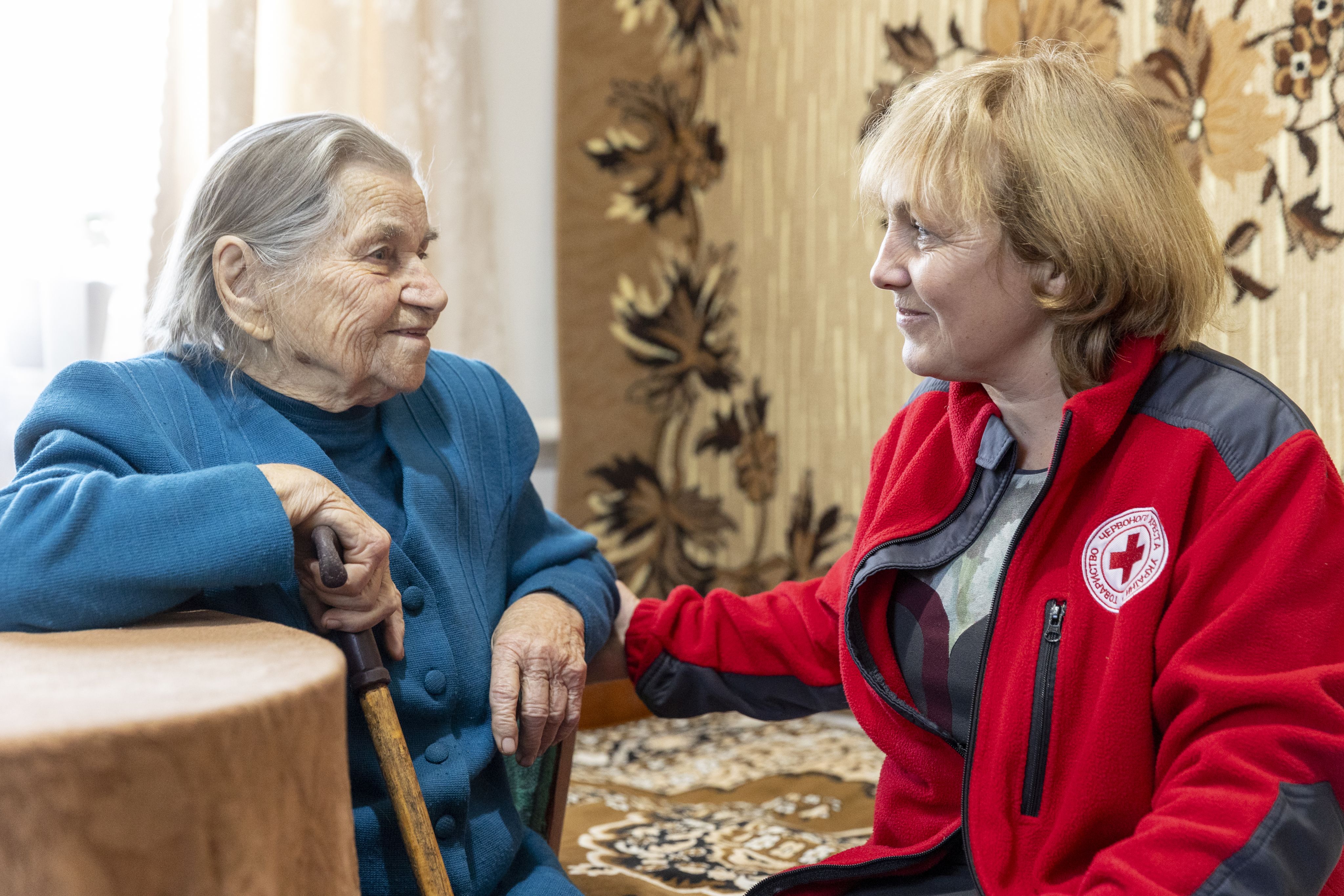 92-year-old Maria Basok shares a smile with and Ukrain Red Cross staffmember Tetyana Kereya as part of the Red Cross’s home-based care initiative in Lanivtsi, Ternopil Oblast, Ukraine.