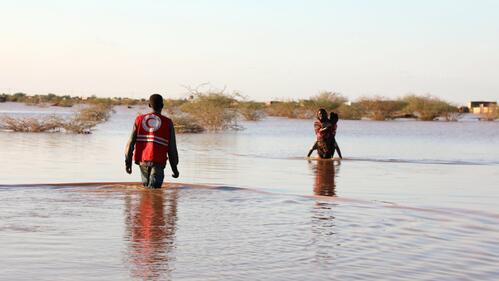 A Sudan Red Crescent Volunteer wades through deep water to reach a woman affected by severe flooding in Khartoum East in August 2020