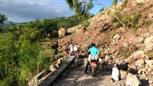 People in Haiti evacuate while navigating landslides caused by the earthquake.