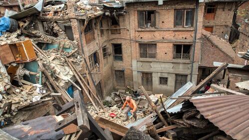 A survivor climbs out of the ruins of buildings in Bhaktapur, Nepal following the devastating earthquake in April 2015
