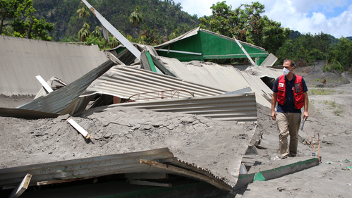 An IFRC operations manager inspects a collapsed food storage building covered in thick ashfall following the eruption of the La Soufriere volcano in April 2021 in Saint Vincent and the Grenadines