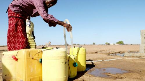 A man in Daadab Sub-county, Kenya fills up jerry cans with clean water from a pump installed by the IFRC during bad drought in summer 2021