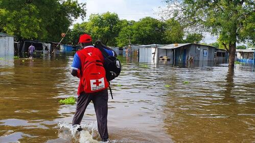 A South Sudan Red Cross volunteer walks through flood water in Bor in September 2020 to reach flood-affected communities and plan a distribution of essential household items