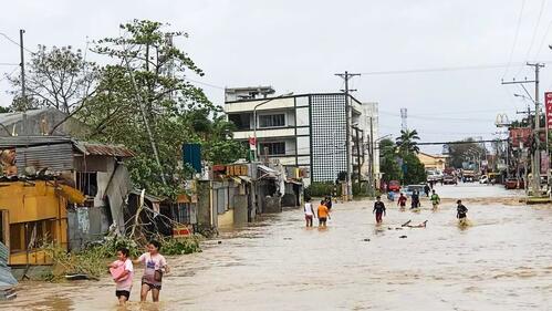 Peoplein Kabankalan City, Philippines wade through a flooded street after Typhoon Odette slammed into the coastal areas of Eastern Philippines on 16 December 2021 causing landslides and widespread flooding.