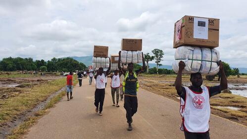 Malawi Red Cross volunteers carry relief supplies on their heads to reach people living in camps who were affected and displaced by Tropical Storm Ana in January 2022.