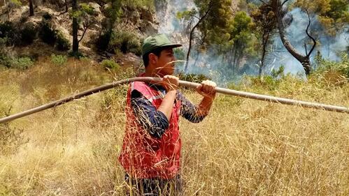 A volunteer from the Tunisian Red Crescent carries a hosepipe to help fight wildfires in Tunisia in August 2021.