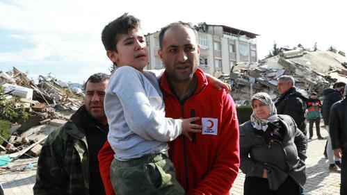 A Turkish Red Crescent volunteer carries a young boy away from the rubble of a collapsed building following two deadly earthquakes n 6 February 2023.