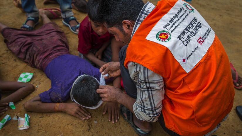 In this file photo from June 22, 2018, a volunteer demonstrates his first aid skills at a disaster simulation drill in Coxs Bazar, Bangladesh. The drill is helping to prepare residents of Kutupalonga 