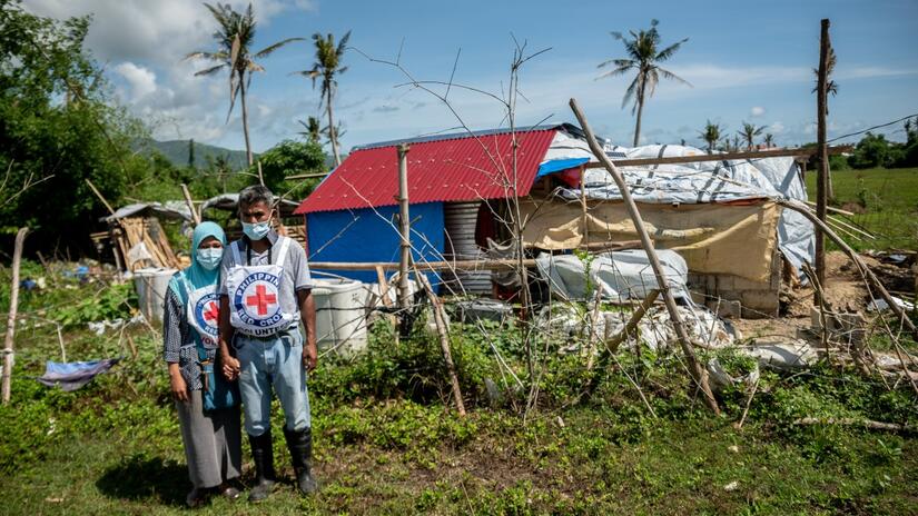 Los voluntarios de la Cruz Roja de Filipinas, Nomalyn y Rene, frente a una casa dañada por el tifón Goni a finales de 2020