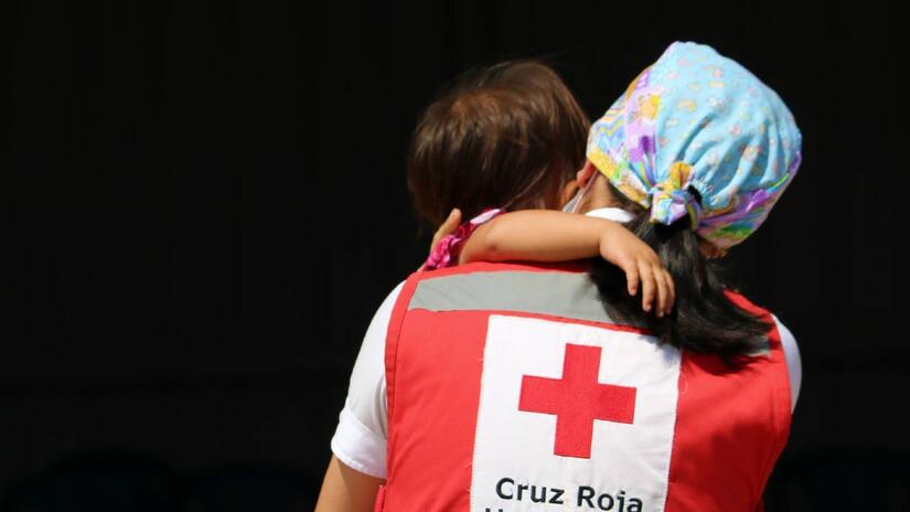 A Honduran Red Cross volunteer carries a small child rescued as part of their response to Hurricane Eta in 2020 which affected millions of people in the region