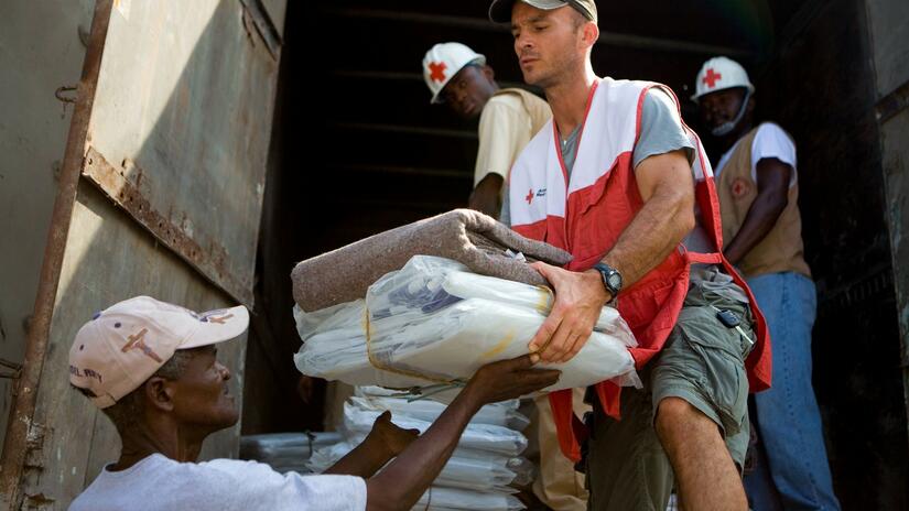 An American Red Cross worker hands supplies to a volunteer from the Haiti Red Cross Society following the earthquake in 2010