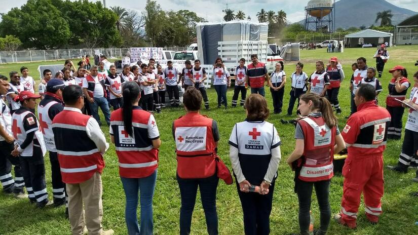 Mexican Red Cross and American Red Cross volunteers stand in a circle and discuss their joint response to the Puebla earthquake in 2018