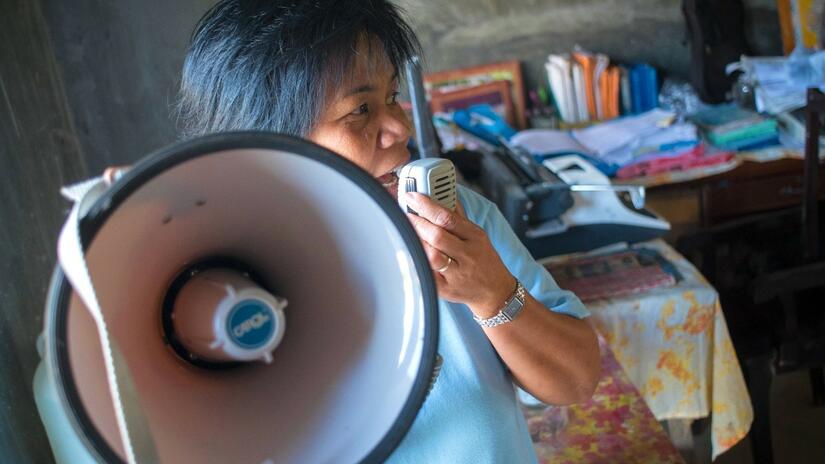 Una voluntaria de la Cruz Roja de Filipinas utiliza un megáfono para compartir mensajes de seguridad con las personas de su comunidad en la isla Panay cuando el tifón Haiyan azotó el país en 2013 