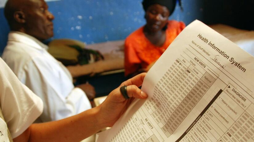A Spanish Red Cross health worker holds a chart detailing outpatient treatment and malaria diagnosis