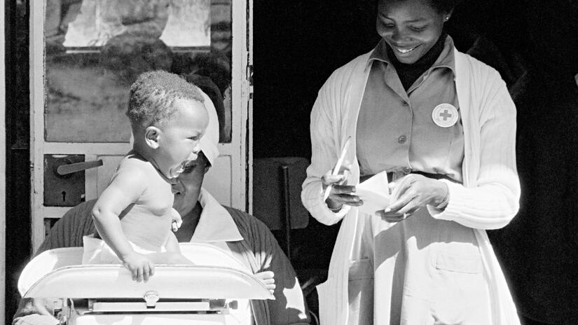 ممرضة من الصليب الأحمر تزن طفلاً في عيادة للأطفال في ملاوي عام 1982