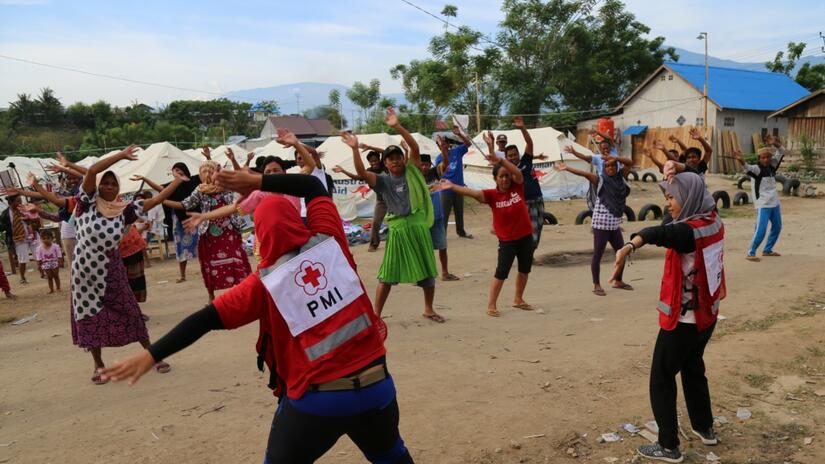 Indonesian Red Cross volunteers lead a psychosocial support session with people affected by an earthquake and resulting tsunami in Central Sulawesi. Support includes morning exercise sessions and readings of the Quran.