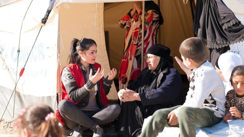An Iraqi Red Crescent Society psychosocial volunteer talks with a family who escaped Mosul to the safety of a relief camp near Dohuk.