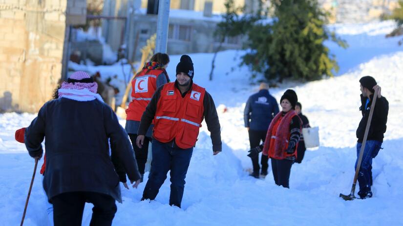 Miembros de la Media Luna Roja de Jordania caminan por Ajloun en 2013 después de una fuerte tormenta de nieve para realizar evaluaciones de necesidades con las comunidades locales y ayudarlas a superar las difíciles condiciones