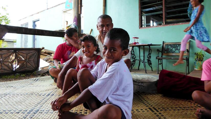A family in Ba District, Fiji who received support from an IFRC cyclone appeal smile and play as the children prepare to return to school