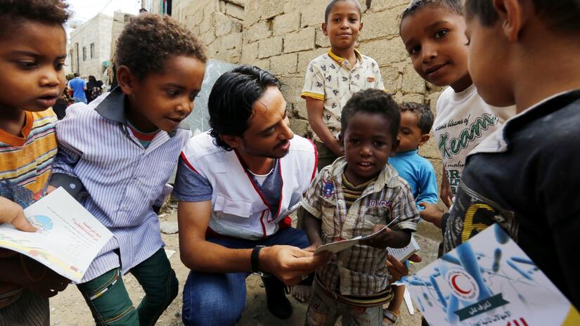 A Yemen Red Crescent volunteer teaches a group of children about washing their hands properly before and after eating to help prevent cholera infection
