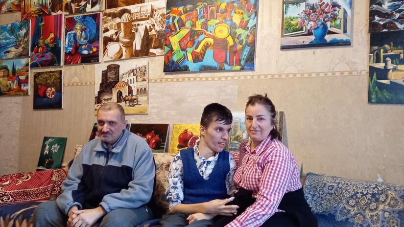 Şiriyeva Rəxşəndə sits with her son Fuad and husband Rəxşəndə in their home