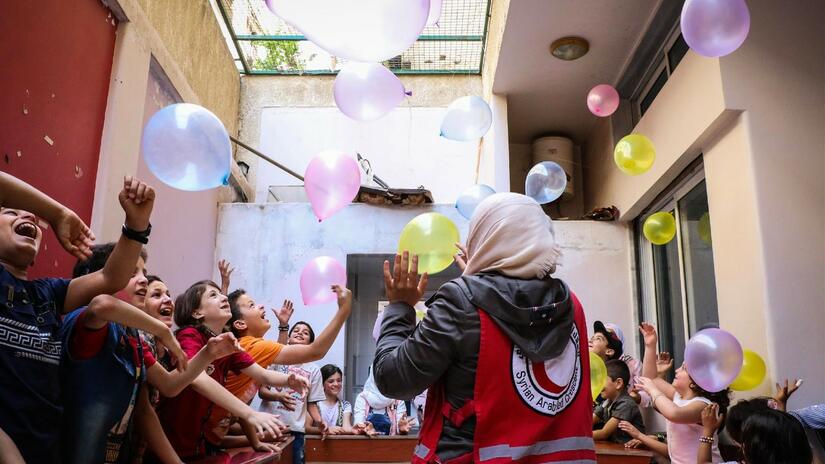 A Syrian Arab Red Crescent volunteer provides psychosocial support to a group of children in August 2021.