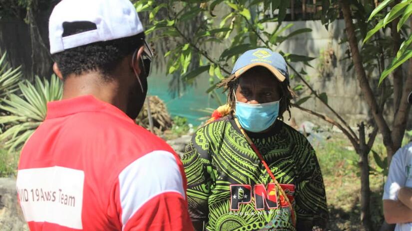 A Papua New Guinea volunteer speaks to a person about taking precautions and safety measures. PNG Red Cross is supporting efforts by the government and health authorities to contain the spread of the virus.