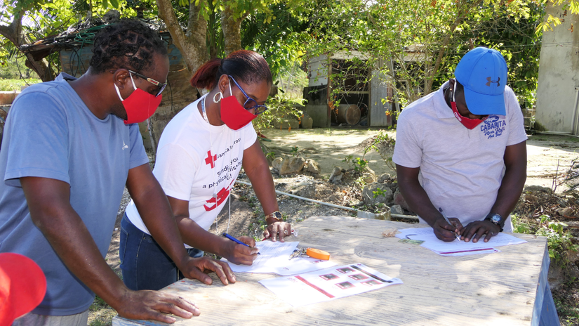 A volunteer from the Jamaica Red Cross helps river raft captains complete the registration process for cash cards, which were issued to persons who lost their income due to COVID-19. Across the Caribbean, persons working in the tourism industry were severely impacted by COVID-19 restrictions.