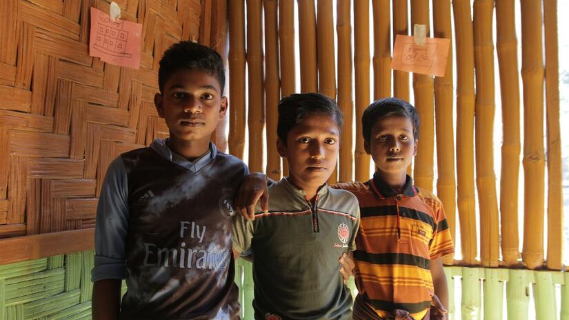 Three young boys, Mohammad, Anwar and Syed stand together in a community safe space run by the Bangladesh Red Crescent Society in Burmapara camp in January 2018